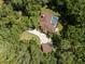 Aerial view of a brown roof house with a screened-in pool, long drive, detached garage, and lots of trees at 35350 County Road 439, Eustis, FL 32726