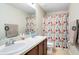 This is a full bathroom with a tub shower combination with colorful curtain and double sink vanity at 356 Giovani Blvd, Clermont, FL 34715