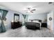 This main bedroom features a ceiling fan, grey wood floors, a bench and an ensuite bathroom at 356 Giovani Blvd, Clermont, FL 34715