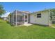 Back exterior view of home featuring an enclosed lanai, lush green yard, and well-maintained siding at 3590 Auburndale Ave, The Villages, FL 32162