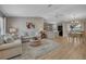Bright living room featuring hardwood floors, neutral paint, comfortable seating, and open access to kitchen at 3590 Auburndale Ave, The Villages, FL 32162