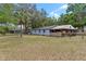 View of the backyard with a covered patio attached to the house and fenced pasture at 43411 State Road 19, Altoona, FL 32702