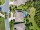 Aerial view of a single-story home with a screened pool, a circular driveway with palm trees and a manicured lawn and landscaping at 4547 Inverness Dr, Leesburg, FL 34748