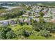 Aerial view of single-story home with screened pool, green lawn and landscaping; community with lake views in the background at 4547 Inverness Dr, Leesburg, FL 34748