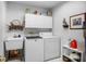 Bright laundry room featuring a utility sink, washer, dryer, cabinets, and tiled floors at 4547 Inverness Dr, Leesburg, FL 34748