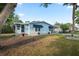 Quaint light blue home with blue awnings, complemented by a well-kept lawn and mature trees at 522 Saint Andrews Blvd, Lady Lake, FL 32159