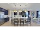Open kitchen with navy cabinets, white quartz island with seating, pendant lights, and stainless steel appliances at 5463 Nickerbean St, Apopka, FL 32712