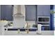 Close-up of kitchen featuring navy cabinets, modern appliances, white backsplash, and quartz countertops at 5463 Nickerbean St, Apopka, FL 32712