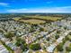 Wide aerial view showcasing a vast residential area with lush greenery, open fields, and a tranquil lake in the distance at 8069 Se 174Th Ludlow Pl, The Villages, FL 32162