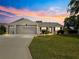 Charming single-story home with a well-manicured lawn and colorful landscaping at dusk at 8069 Se 174Th Ludlow Pl, The Villages, FL 32162