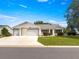 A home featuring a multi-car garage, lovely lawn and shrubbery at 8069 Se 174Th Ludlow Pl, The Villages, FL 32162