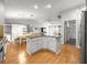 Open concept kitchen with granite island, white cabinets, stainless appliances, and hardwood floors at 8069 Se 174Th Ludlow Pl, The Villages, FL 32162