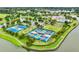 This stunning aerial view showcases the community tennis and shuffleboard courts with a scenic lake and lush landscaping at 8167 Bridgeport Bay Cir, Mount Dora, FL 32757