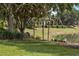 Lush backyard with mature trees, a serene pond, and glimpses of surrounding houses at 8167 Bridgeport Bay Cir, Mount Dora, FL 32757