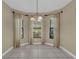 Bright dining area featuring tile floors, three windows with curtains and a hanging chandelier at 8167 Bridgeport Bay Cir, Mount Dora, FL 32757