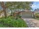 Charming home with lush landscaping and a stone-accented facade and a two-car garage, all shaded by a mature tree at 8167 Bridgeport Bay Cir, Mount Dora, FL 32757