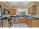 Modern kitchen with stainless steel appliances, wooden cabinets, and tile flooring, all within an open layout at 8167 Bridgeport Bay Cir, Mount Dora, FL 32757