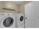 Functional laundry room with white washer and dryer, with wire rack for storing supplies at 8167 Bridgeport Bay Cir, Mount Dora, FL 32757