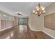 Open-concept living room with hardwood floors, ceiling fan, chandelier and sliding glass doors to a screened patio at 8167 Bridgeport Bay Cir, Mount Dora, FL 32757
