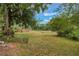 Large backyard with mature trees, a small bench and partial fencing at 8410 Lake Bosse Dr, Orlando, FL 32810