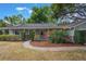 Inviting single-story home features a quaint, covered porch, surrounded by vibrant plants and a well-manicured garden at 8410 Lake Bosse Dr, Orlando, FL 32810