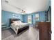 Bright bedroom with hardwood floors, a comfortable bed, and decorative accents in blue tones at 8869 Se 159Th Pl, Summerfield, FL 34491
