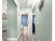 Hallway leading to the bathroom and bedroom, complete with stylish flooring and pastel green walls at 8869 Se 159Th Pl, Summerfield, FL 34491