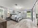 A main bedroom with a king bed, floral wallpaper, and barn doors to the bathroom at 8869 Se 159Th Pl, Summerfield, FL 34491
