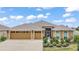 Beautiful exterior showcasing a well-manicured lawn, landscaping, and a three car garage at 892 Hubbard Loop, The Villages, FL 32163