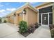 Side view of a home showcasing a three-car garage, manicured shrubs, and a screened front entry way at 892 Hubbard Loop, The Villages, FL 32163