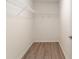 Walk-in closet featuring white wire shelving and durable wood-look flooring at 9181 Se 166Th Sprung Ln, The Villages, FL 32162