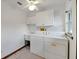 Bright laundry room with washer, dryer, utility sink, white cabinets and a ceiling fan at 9236 County Road 48, Yalaha, FL 34797