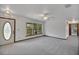 Bright living room featuring plush carpeting, a ceiling fan, fresh white walls, and natural light from a window at 9236 County Road 48, Yalaha, FL 34797