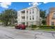 A corner exterior view of a three-story condo building with balconies and red car in a parking area at 1021 Siena Park Blvd # 204, Kissimmee, FL 34747