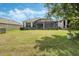 Spacious backyard featuring lush green grass, screened-in lanai and mature landscaping at 1027 Timbervale Trl, Clermont, FL 34715