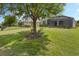 Lush green backyard with mature trees, landscaping, and a view of the screened-in lanai at 1027 Timbervale Trl, Clermont, FL 34715