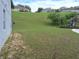 Exterior view of a grassy backyard with a playground and houses on a small hill in the distance at 1033 N Jacks Lake Rd, Clermont, FL 34711