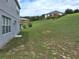 Exterior backyard view from the back of the house with green grass and some neighborhood homes on a small hill at 1033 N Jacks Lake Rd, Clermont, FL 34711