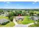 Wide aerial shot of a tan home in a residential area, featuring a long driveway and lush greenery at 10465 Se 41St Ter, Belleview, FL 34420