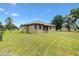 View of a tan stucco home with a well-maintained lawn and a storage shed, perfect for outdoor enjoyment at 10465 Se 41St Ter, Belleview, FL 34420