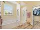 Bright bathroom with a soaking tub, glass-enclosed shower, and walk-in closet access at 10465 Se 41St Ter, Belleview, FL 34420
