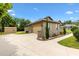 Side view of a tan stucco home featuring stone accents, a two-car garage, a well-manicured lawn, and a storage shed at 10465 Se 41St Ter, Belleview, FL 34420