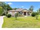 Charming single-story home with a well-manicured lawn, stone accents, and a welcoming front porch with rocking chairs at 10465 Se 41St Ter, Belleview, FL 34420