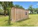 Close-up of a wooden storage shed with double doors and a small window, situated in a well-kept backyard at 10465 Se 41St Ter, Belleview, FL 34420