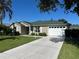 Charming single-story home with well-manicured lawn and a two-car garage on a sunny day at 1060 Davenport Dr, The Villages, FL 32162