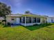 View of the sunroom with many windows, door and landscaped yard on a bright day at 1060 Davenport Dr, The Villages, FL 32162