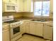 Bright kitchen featuring white cabinets, tile countertops, and standard appliances at 1100 Martinique Dr # 105, Winter Haven, FL 33884