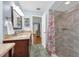Bathroom with dual sinks, granite countertops, and a tiled shower with floral curtain at 111 Ridgeview Cir, Eustis, FL 32726