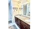Bathroom featuring double sinks with granite countertops and a large mirror above dark wood cabinets at 11277 Se 170Th Ln, Summerfield, FL 34491