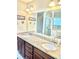 Bathroom featuring double sinks with granite countertops and a large mirror above dark wood cabinets at 11277 Se 170Th Ln, Summerfield, FL 34491
